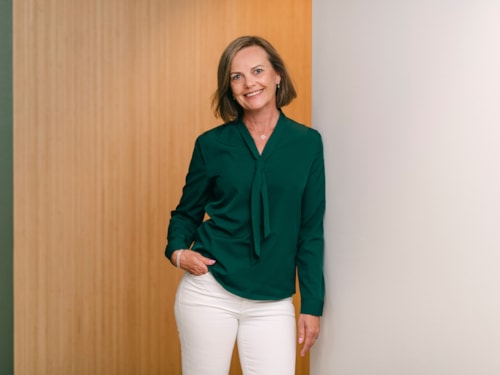 Portrait of employee Eva Brurberg wearing a green blouse and white pants