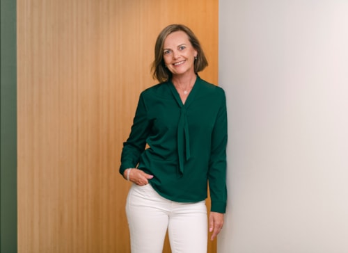 Portrait of employee Eva Brurberg wearing a green blouse and white pants